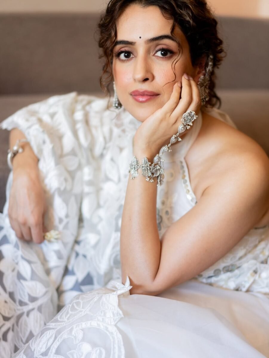 Sanya Malhotra posing in a white halter-neck outfit with heavy silver filigree ear-cuffs and a traditional hathphool